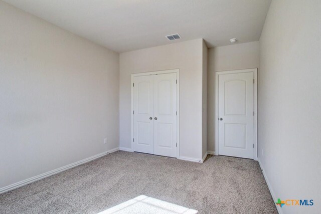 unfurnished bedroom with a closet and light colored carpet