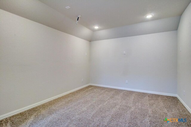 carpeted empty room with lofted ceiling