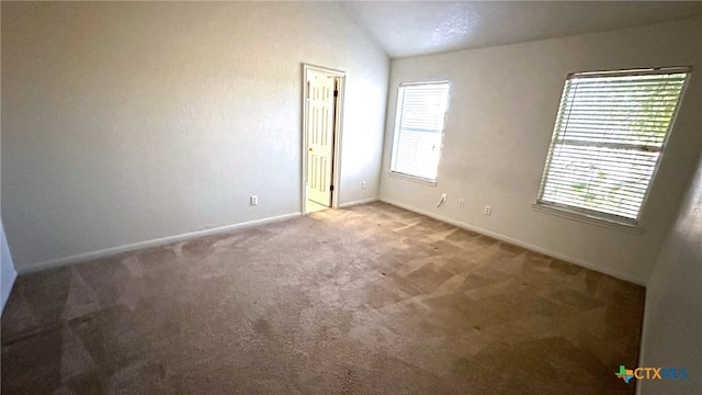 carpeted spare room featuring a wealth of natural light and vaulted ceiling