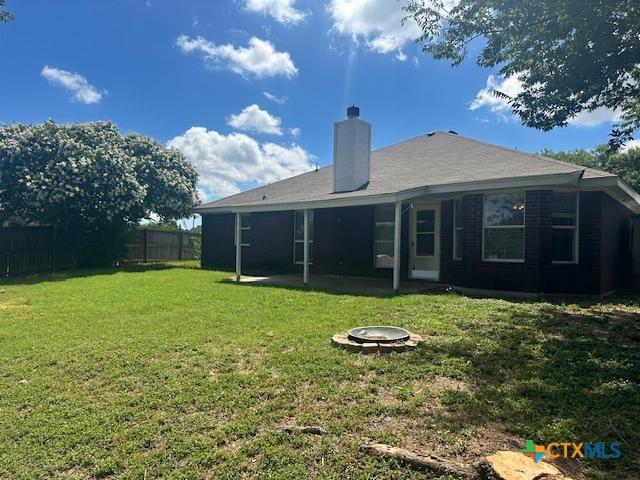 1302 Creek St, Copperas Cove, TX 76522 - back of house featuring a fenced backyard, an outdoor fire pit, and a chimney