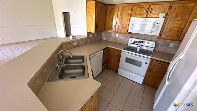 kitchen featuring light tile patterned flooring, sink, kitchen peninsula, white appliances, and decorative backsplash