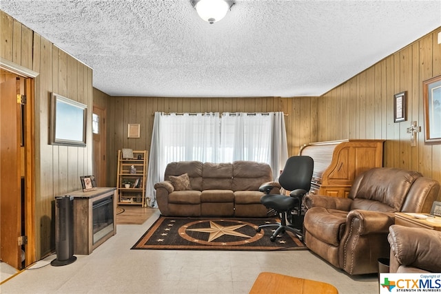 living room featuring wooden walls and a textured ceiling