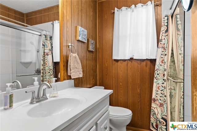 bathroom featuring vanity, toilet, a textured ceiling, and wooden walls