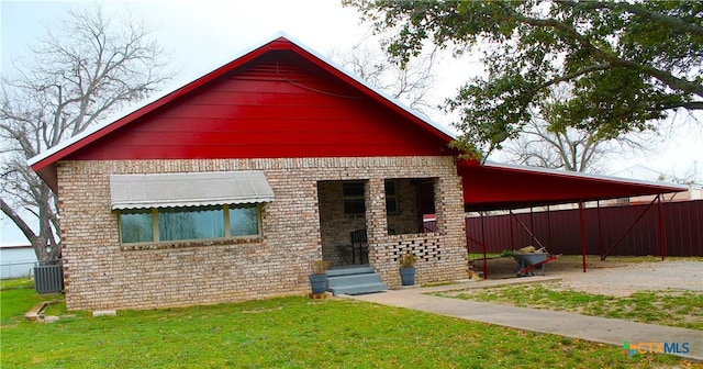 rear view of house with cooling unit, a carport, and a yard