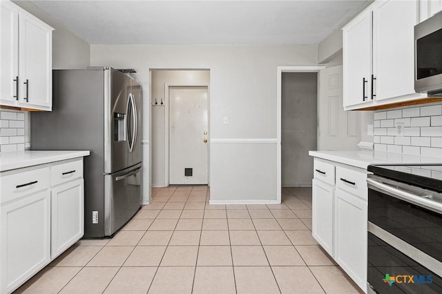 kitchen with backsplash, appliances with stainless steel finishes, white cabinets, and light countertops