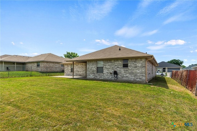 rear view of house featuring a lawn, a fenced backyard, and brick siding