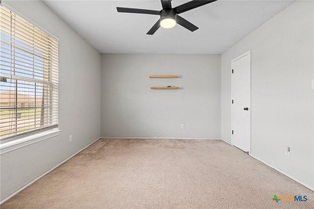 empty room with ceiling fan, baseboards, carpet flooring, and plenty of natural light