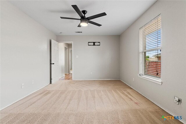 unfurnished room with light carpet, baseboards, visible vents, and ceiling fan