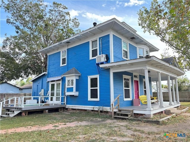 rear view of house featuring a wall mounted air conditioner, covered porch, and a deck