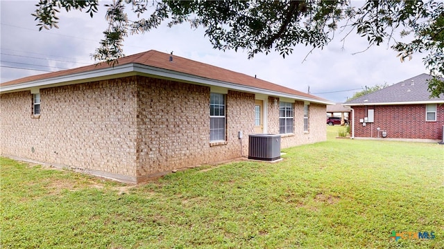 901 E Sarah St, Cuero, TX 77954 - back of house featuring central AC unit, a yard, and brick siding