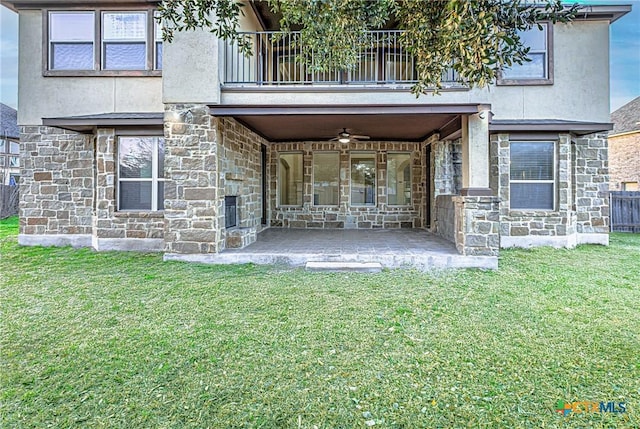 exterior space with ceiling fan, a yard, a balcony, a patio area, and stone siding