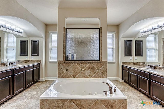 full bath with a sink, two vanities, and a jetted tub