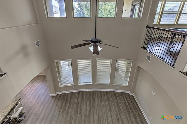 unfurnished living room featuring visible vents, a healthy amount of sunlight, wood finished floors, and a ceiling fan