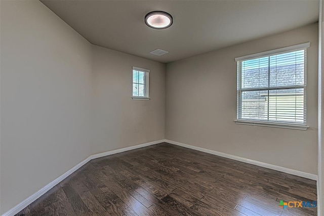 spare room with visible vents, baseboards, and dark wood-style flooring