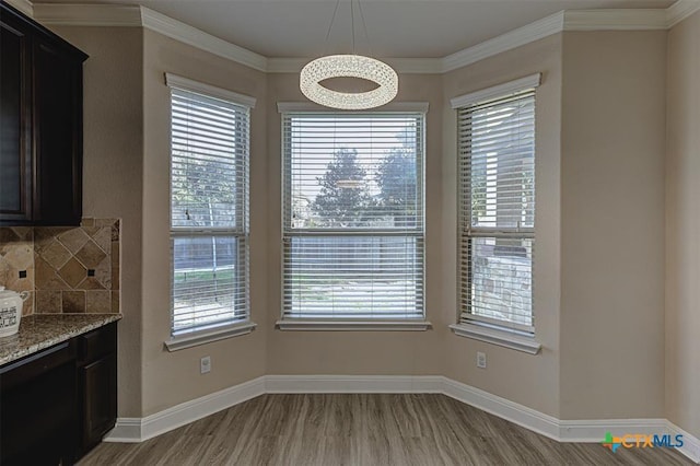 unfurnished dining area featuring crown molding, a wealth of natural light, and light wood finished floors