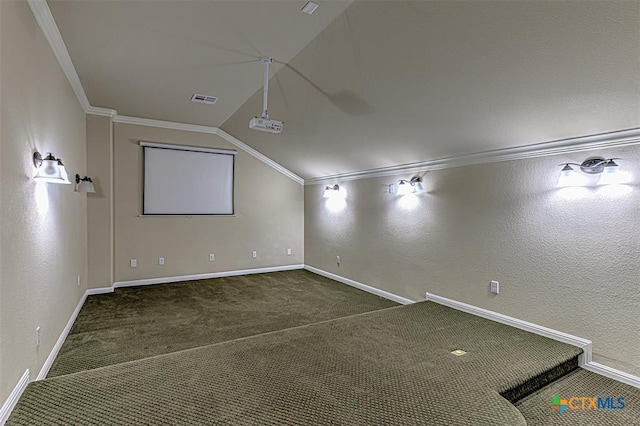 carpeted home theater room with visible vents, lofted ceiling, baseboards, and ornamental molding