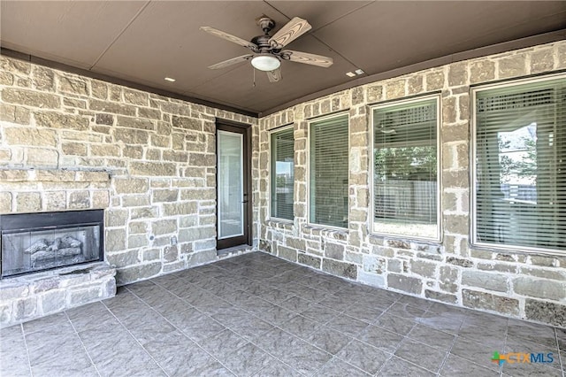 view of patio featuring an outdoor stone fireplace and a ceiling fan