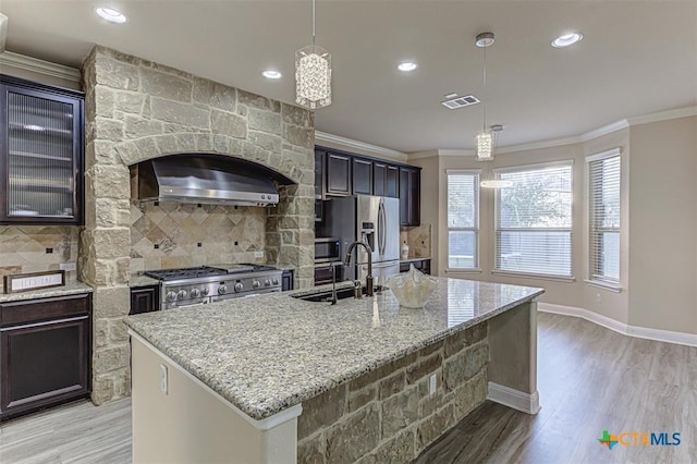 302 N Frontier Ln, Cedar Park, TX 78613 - kitchen featuring appliances with stainless steel finishes, ornamental molding, exhaust hood, light stone countertops, and decorative backsplash
