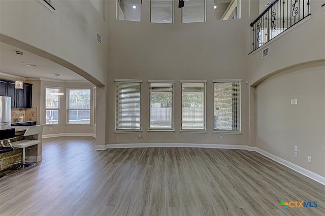 living area with visible vents, light wood-type flooring, baseboards, and ornamental molding