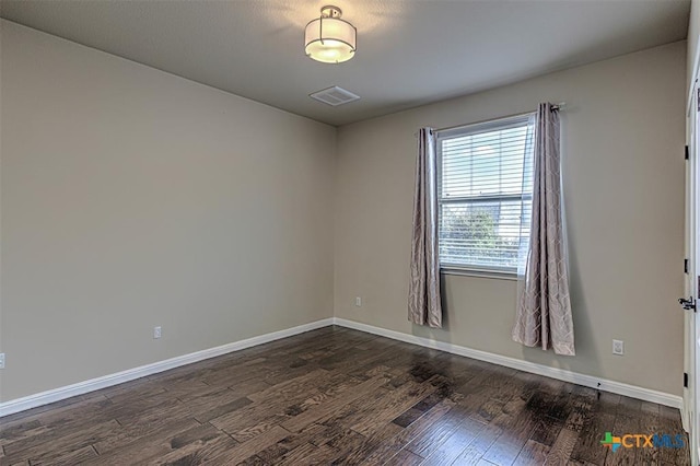 empty room featuring visible vents, baseboards, and dark wood-type flooring