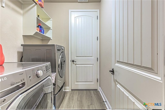 clothes washing area with laundry area, light wood-type flooring, baseboards, and separate washer and dryer