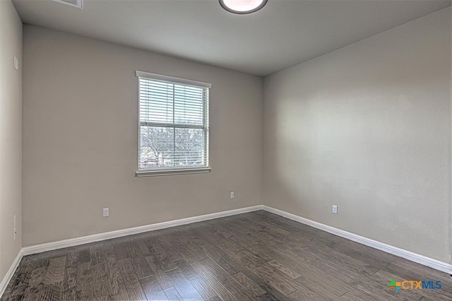 empty room with dark wood finished floors and baseboards