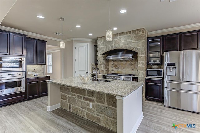 kitchen featuring a sink, light stone counters, stainless steel appliances, crown molding, and decorative backsplash