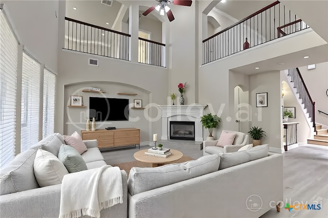 302 N Frontier Ln, Cedar Park, TX 78613 - living room with a towering ceiling, ceiling fan, stairway, wood finished floors, and a glass covered fireplace