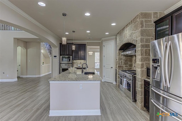 302 N Frontier Ln, Cedar Park, TX 78613 - kitchen featuring stainless steel appliances, ornamental molding, arched walkways, a kitchen island with sink, and light stone countertops