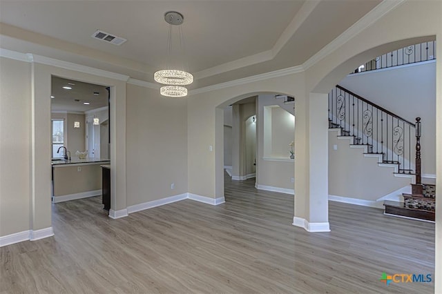 interior space with light wood-type flooring, visible vents, arched walkways, and an inviting chandelier