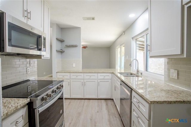 kitchen featuring visible vents, light wood-style flooring, stainless steel appliances, white cabinetry, and a sink