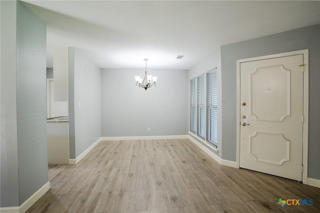 entryway with visible vents, baseboards, light wood-type flooring, and a chandelier