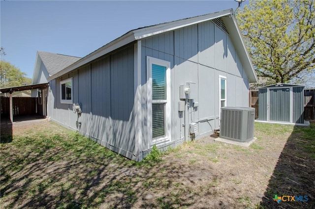 rear view of property featuring an outbuilding, a shed, central AC, and fence