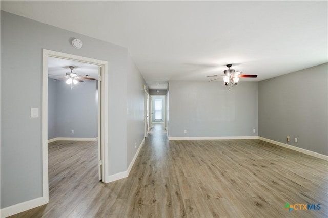 empty room featuring wood finished floors, baseboards, and ceiling fan