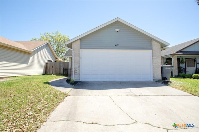view of front of property featuring brick siding, a front yard, fence, and a garage