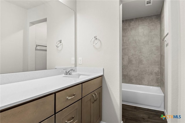 128 Bluestem Dr, Elgin, TX 78621 - bathroom featuring wood finished floors, vanity, tub / shower combination, and baseboards