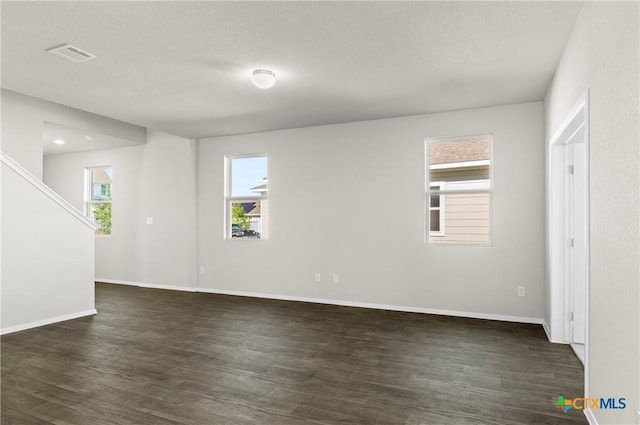 128 Bluestem Dr, Elgin, TX 78621 - empty room with dark wood-style flooring, baseboards, a textured ceiling, and stairs