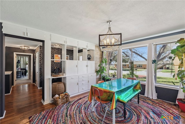 dining room with a textured ceiling, wood finished floors, and an inviting chandelier