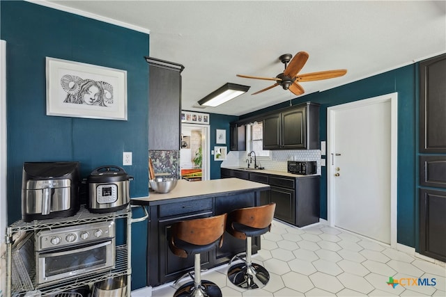 kitchen with wall oven, decorative backsplash, a ceiling fan, light countertops, and a sink