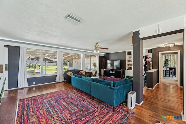 living room featuring a ceiling fan, a textured ceiling, visible vents, and wood finished floors