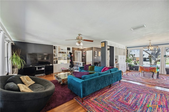 living area with ceiling fan, visible vents, and wood finished floors