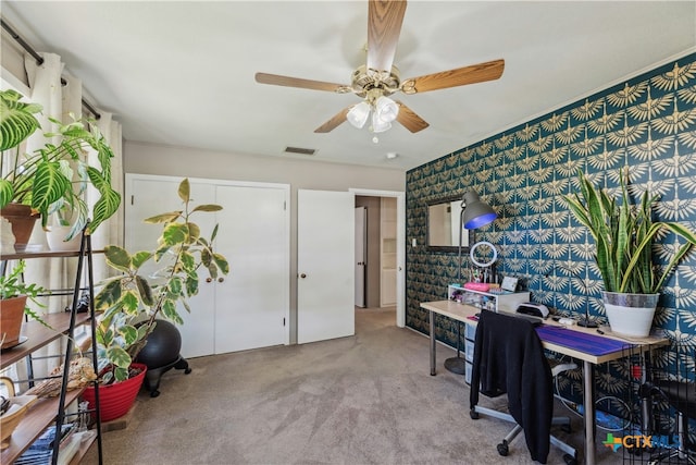 carpeted office space with visible vents, ceiling fan, and wallpapered walls