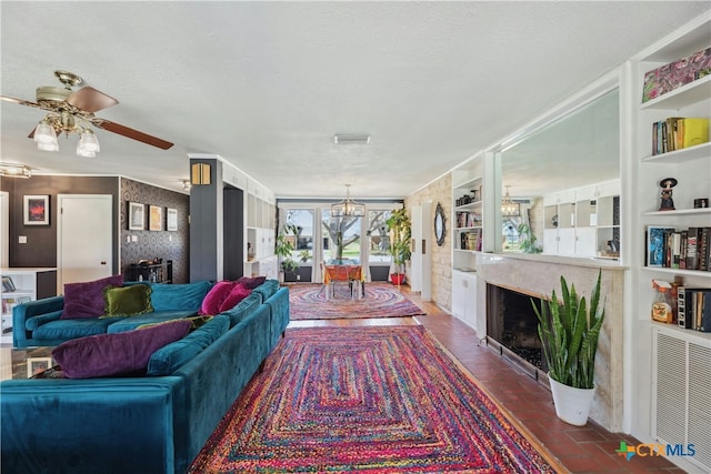 living area featuring visible vents, a high end fireplace, brick floor, a textured ceiling, and ceiling fan with notable chandelier