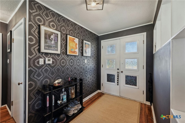 entrance foyer featuring ornamental molding, a textured ceiling, and wallpapered walls