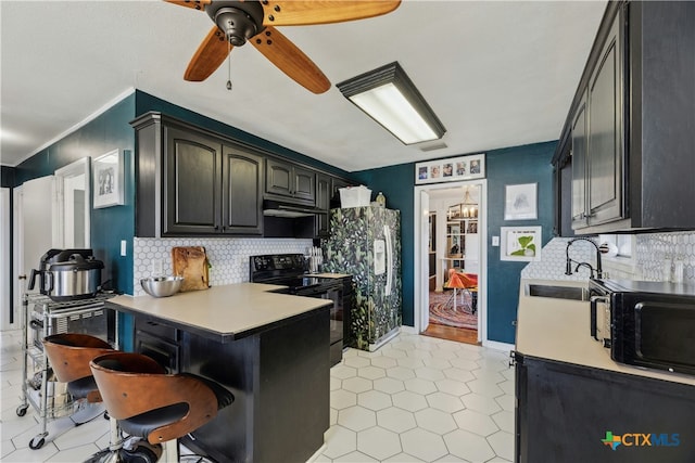 kitchen with a peninsula, a sink, decorative backsplash, black appliances, and a kitchen bar