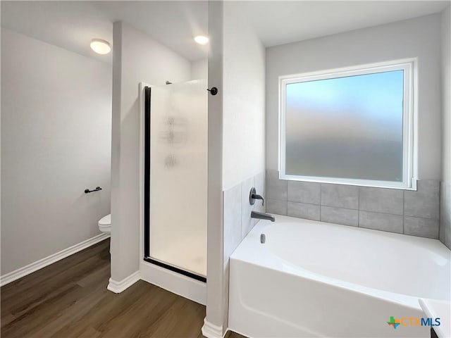 bathroom with toilet, plus walk in shower, plenty of natural light, and hardwood / wood-style flooring