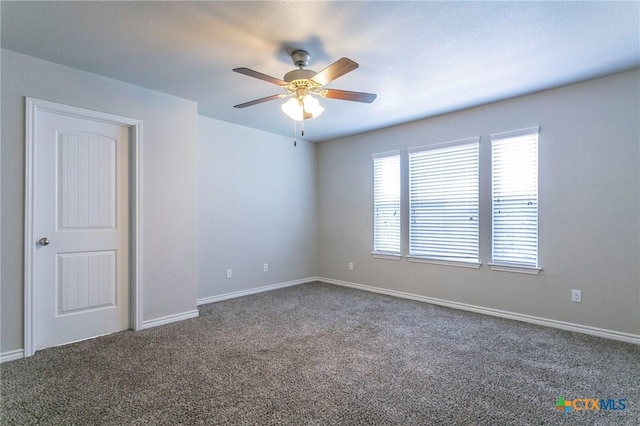 spare room featuring dark colored carpet and ceiling fan