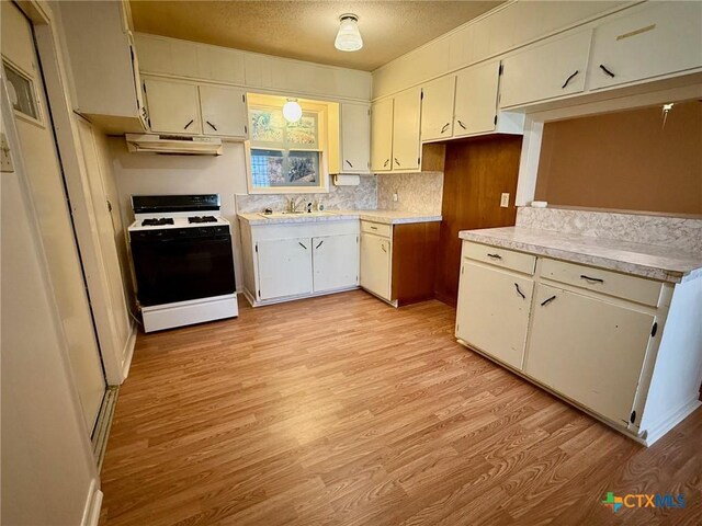 3502 E Juan Linn St, Victoria, TX 77901 - kitchen with white gas range oven, under cabinet range hood, light wood-type flooring, light countertops, and a sink