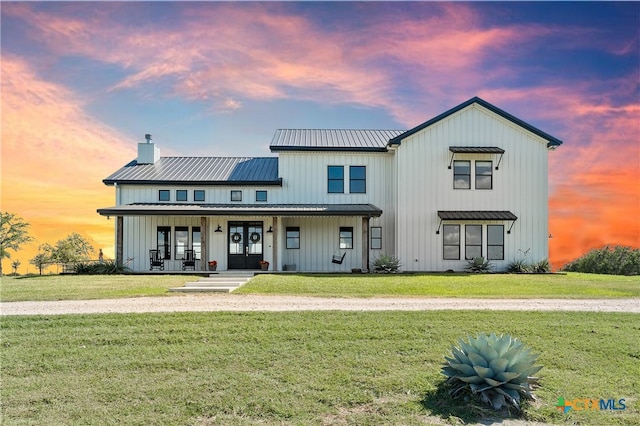 modern inspired farmhouse featuring covered porch and a yard