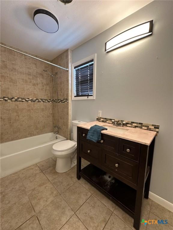 full bathroom featuring tile patterned floors, vanity, toilet, and tiled shower / bath